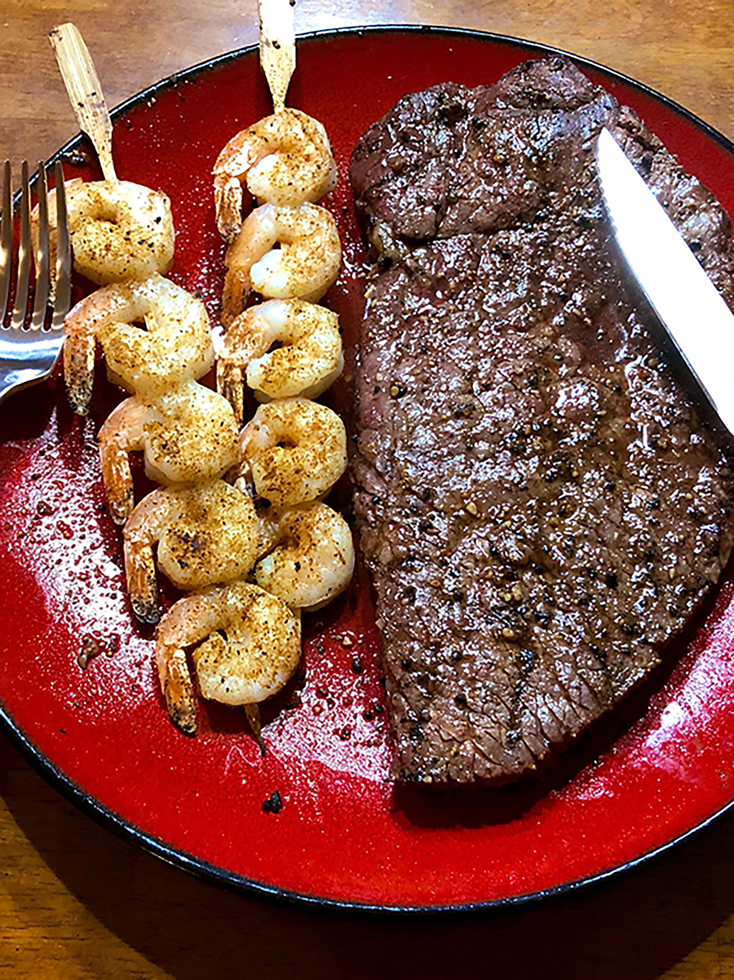 Steak on a plate with shrimp skewers.